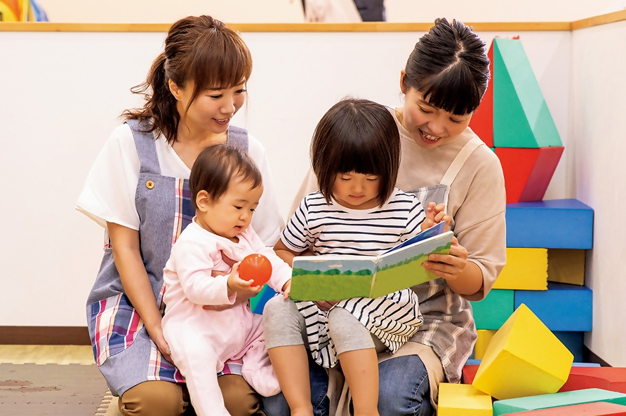 写真：保育園で読み聞かせを行う保育士と子どもの様子